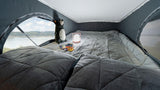 Cozy RV rental sleeping area with a quilted bed, soft pillows, and a scenic lake view from the large window.