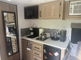 Functional RV rental kitchen: microwave, stove, coffee maker, fridge, and pet-friendly touches for cozy travel.