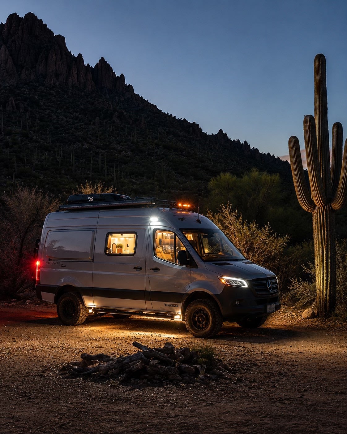 An illuminated Winnebago Revel camper van sits in a desert scene at night — photo 1