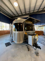 Polished Airstream travel trailer (RV) on display, ideal for your next rv rental adventure. Its front window guard is open.