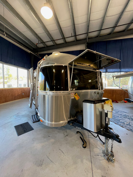 Polished Airstream travel trailer (RV) on display, ideal for your next rv rental adventure. Its front window guard is open.