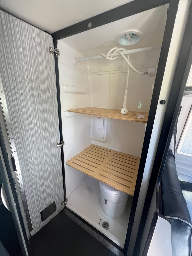  ocean & sand outside van door.|Your next RV rental adventure: A beige camper van parked on a dirt road with large desert rock formations.|Desert camping with an RV rental — photo 6