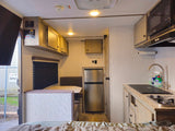 Cozy rv rental interior with kitchenette, dinette, and sleeping space. Features fridge, stove, microwave for travel comfort.
