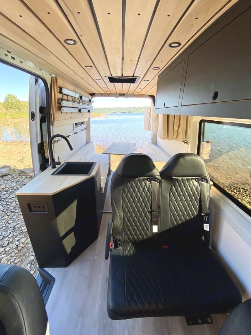 Your next rv rental awaits! White van parked before grand red rock mountains bathed in warm sunset light. Perfect for outdoor travel.|Cozy RV rental interior with beach & ocean views. Perfect for mobile living — photo 10