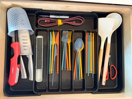 Neatly organized RV rental kitchen drawer with colorful compact utensils, knives, and tools, perfect for camping efficiency.