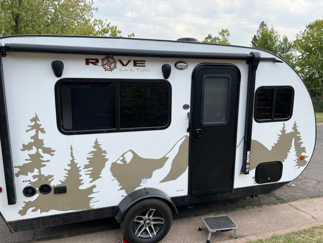 Compact white Rove travel trailer with black accents and a scenic mountain/tree decal, ready for your next RV rental adventure.
