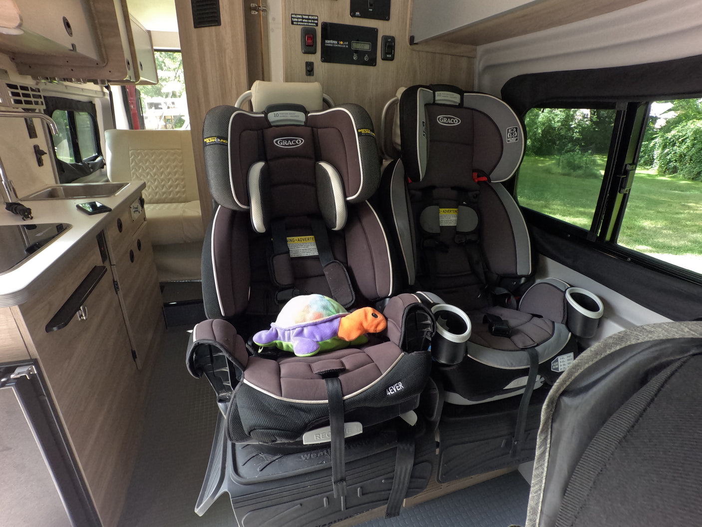Family-friendly RV rental interior featuring two child safety seats, a kitchen, and a dinette, ready for travel with kids.