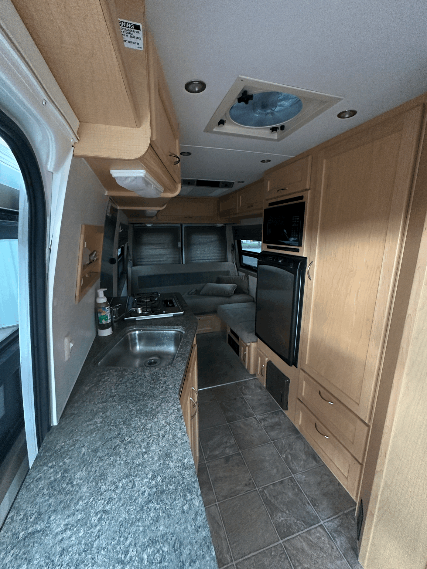 Efficient RV rental interior showcasing a compact kitchen with sink, stove, microwave, fridge, and comfortable living space.