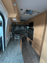 Efficient RV rental interior showcasing a compact kitchen with sink, stove, microwave, fridge, and comfortable living space.