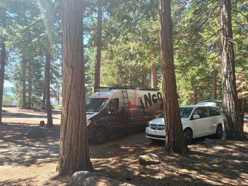 Two vehicles, including an RV rental van (Vanco Medical), parked among tall trees at a sunny lakeside campsite. Great for camping! — photo 12