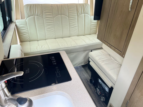 Spacious RV rental interior: cream sofa, induction cooktop, sink, and wood-look cabinets. Enjoy comfy travels!
