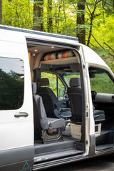 Spacious camper van interior, perfect for your next rv rental adventure. Open door reveals comfy seats and overhead storage in nature.