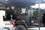 A rugged black Expedition 2.0 off-road trailer with an open side revealing an integrated outdoor kitchen, ideal for rv rental adventures.