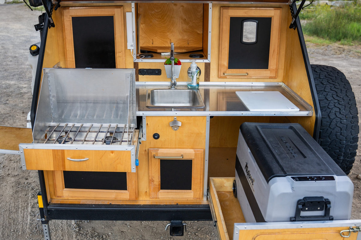 Compact RV rental kitchen: pull-out stove, sink, countertop, and fridge, ideal for outdoor cooking. — photo 10