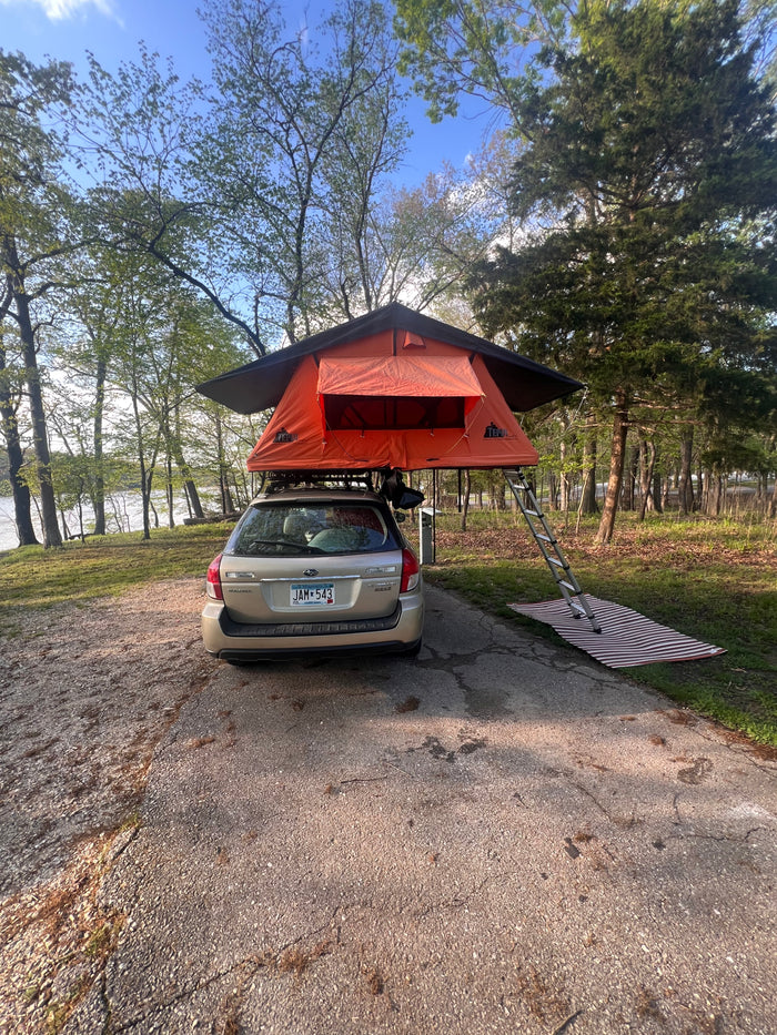 Rooftop tent camping with a Subaru Outback by the water, a compact option instead of an RV rental for outdoor adventure.