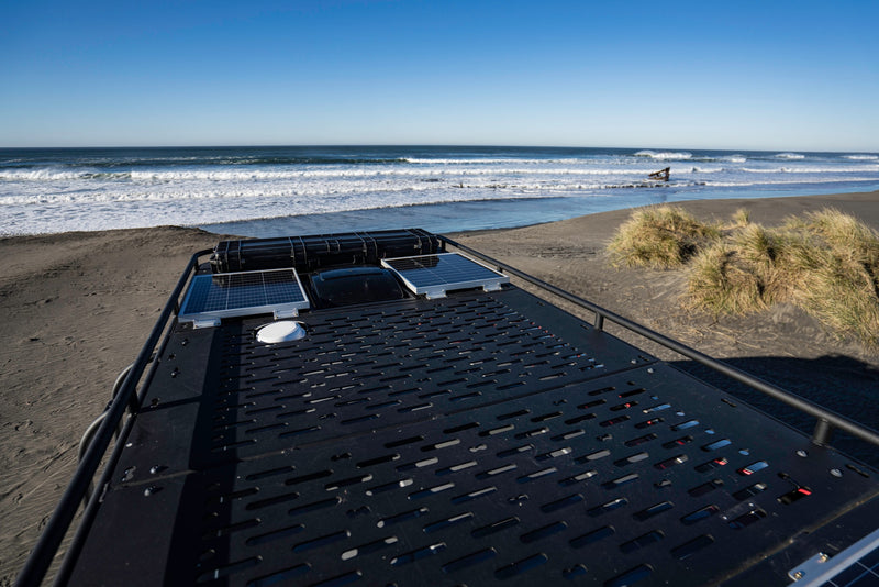 RV rental rooftop gear (solar panels, storage) overlooking a sandy beach with ocean waves, dunes, and a shipwreck. — photo 22