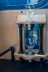 Custom RV rental interior featuring an innovative wooden wine glass storage system with two glasses and black pipe supports.