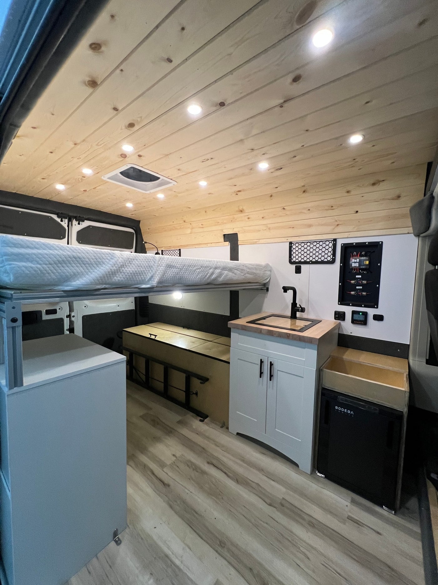  and fridge.|A custom RV rental interior featuring an elevated bed — photo 3