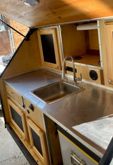 Compact rv rental galley with stainless steel sink, counter, and ample storage. Fully equipped.