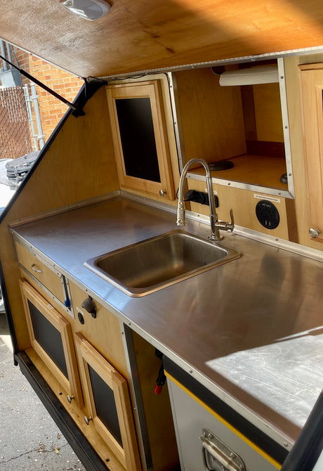 Compact rv rental galley with stainless steel sink, counter, and ample storage. Fully equipped.