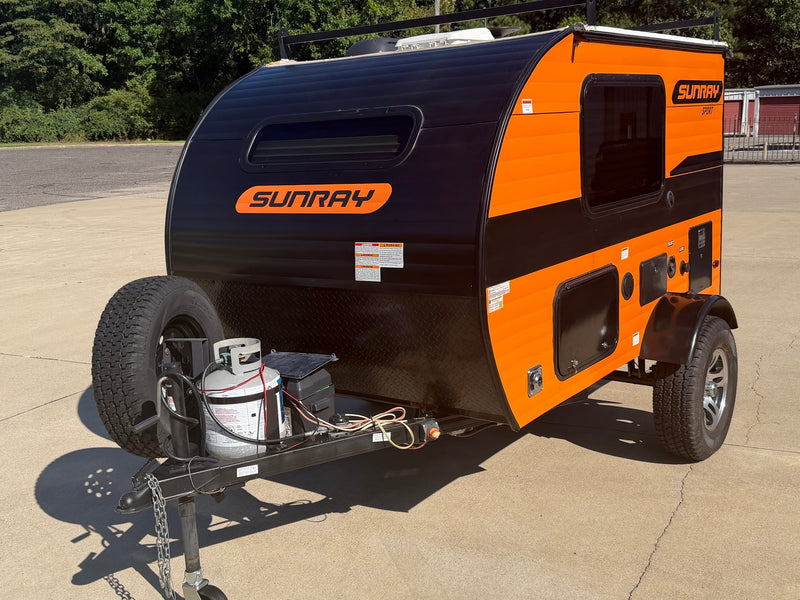 Bright orange & black Sunray teardrop RV rental parked — photo 1