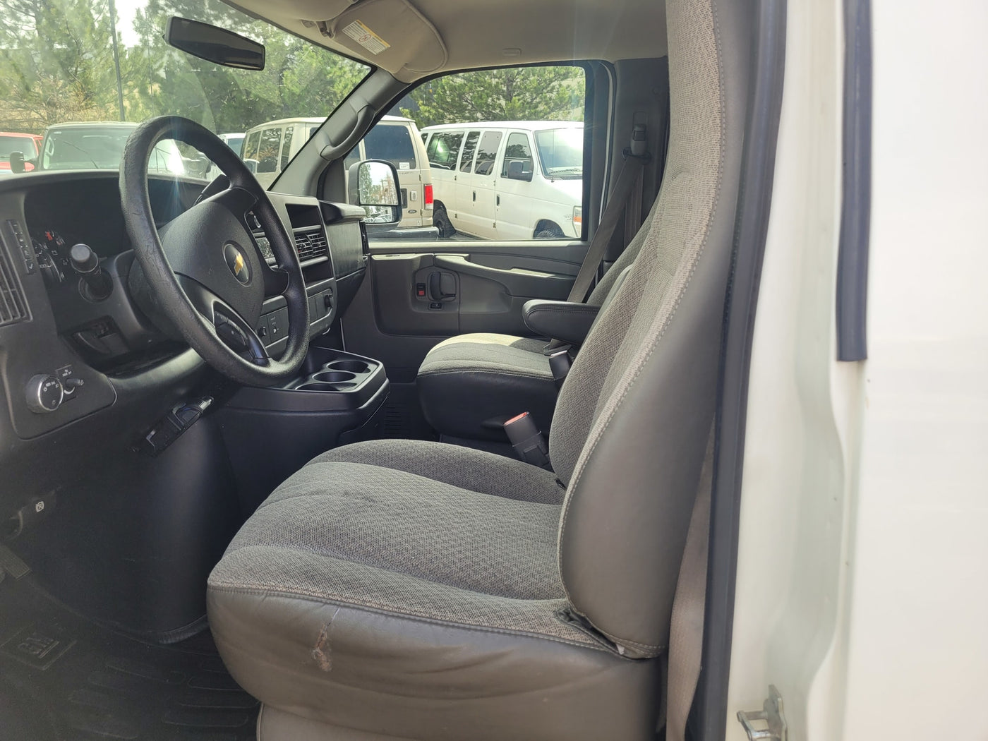 Driver's cockpit of a work van, possibly for rv rental. Shows steering wheel, dashboard, and front seats with wear. — photo 9