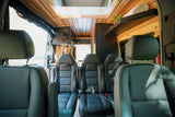Spacious RV rental interior with wooden ceilings, multiple comfortable seats, custom controls, and storage, ideal for road trips.