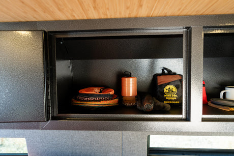 Organized RV rental interior showcasing textured storage compartments filled with outdoor gear like Wise Owl towels and camping essentials.