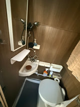 Our RV rental offers a compact wet bath with a functional shower, corner sink, and toilet for your travel comfort.