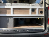 Spacious RV rental interior features a custom bed platform with under-bed storage, built-in cabinet, and warm lighting.