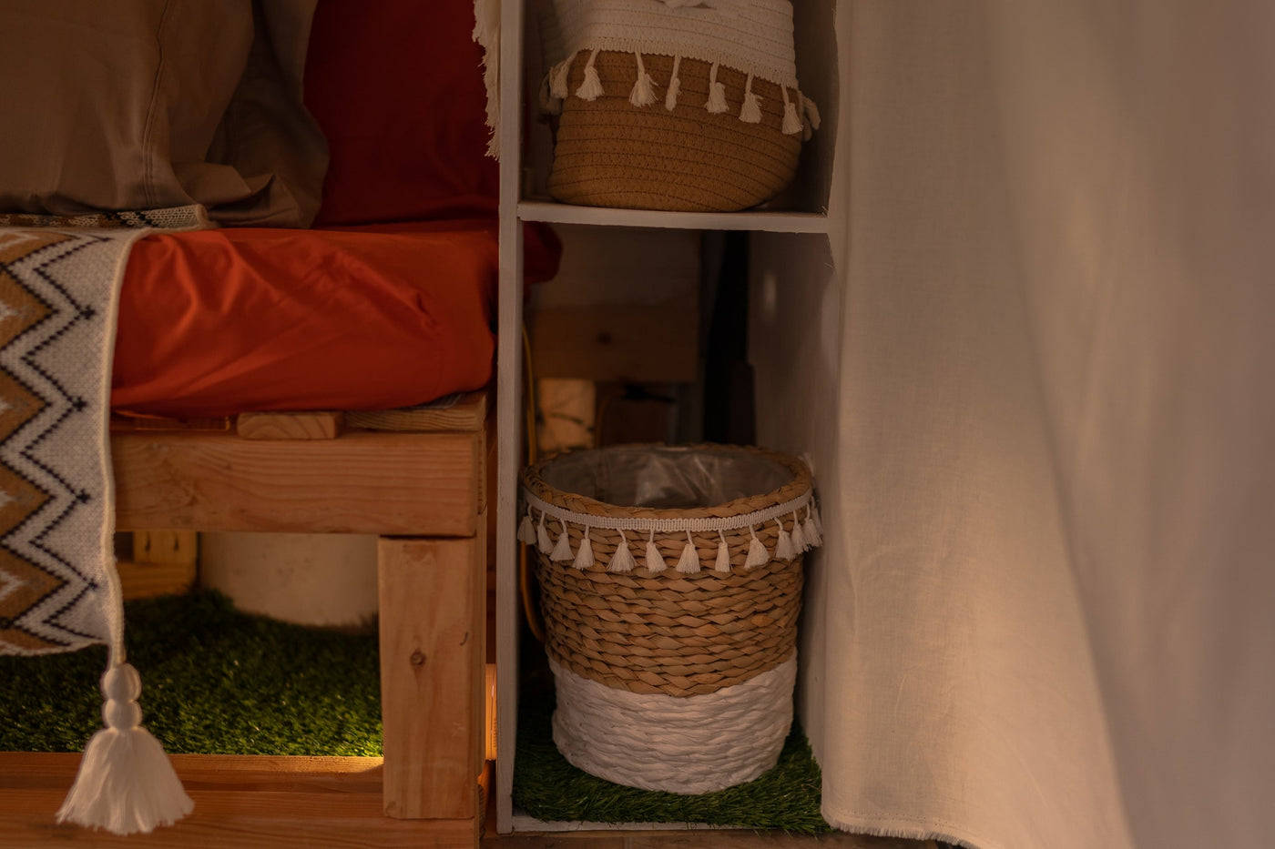Cozy RV rental interior with elevated bed, woven storage baskets, and artificial grass accents. — photo 16