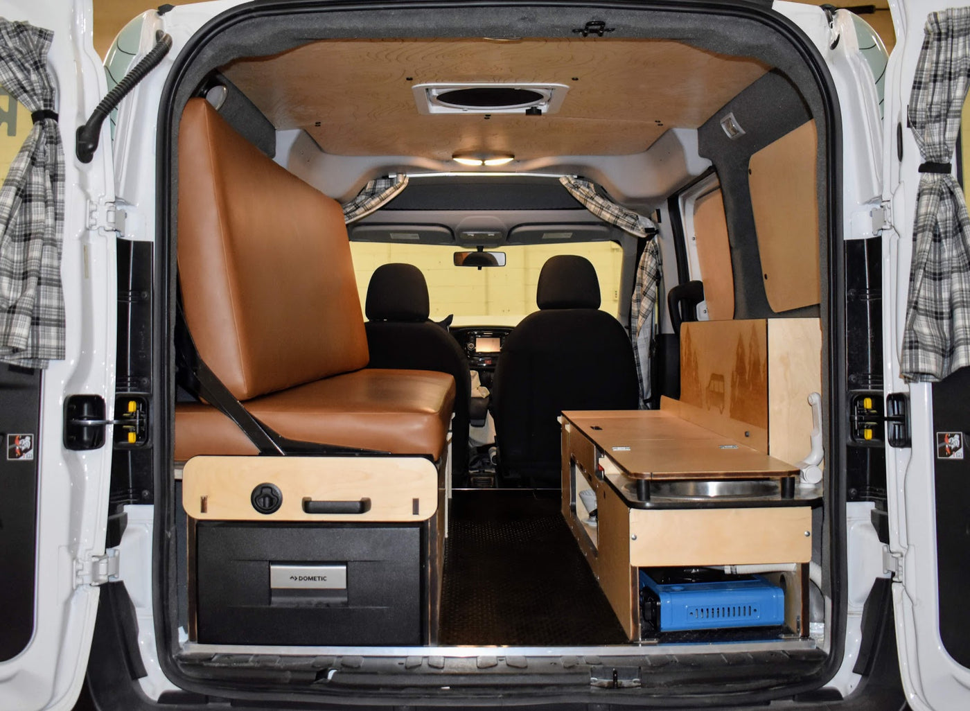 RV rental camper van interior: features a brown bench/bed, Dometic fridge, and wooden kitchenette with a stove. — photo 5