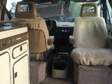 RV rental: Looking into a cozy Westfalia camper van cockpit, showing fluffy front seats and a built-in kitchen unit on the left.