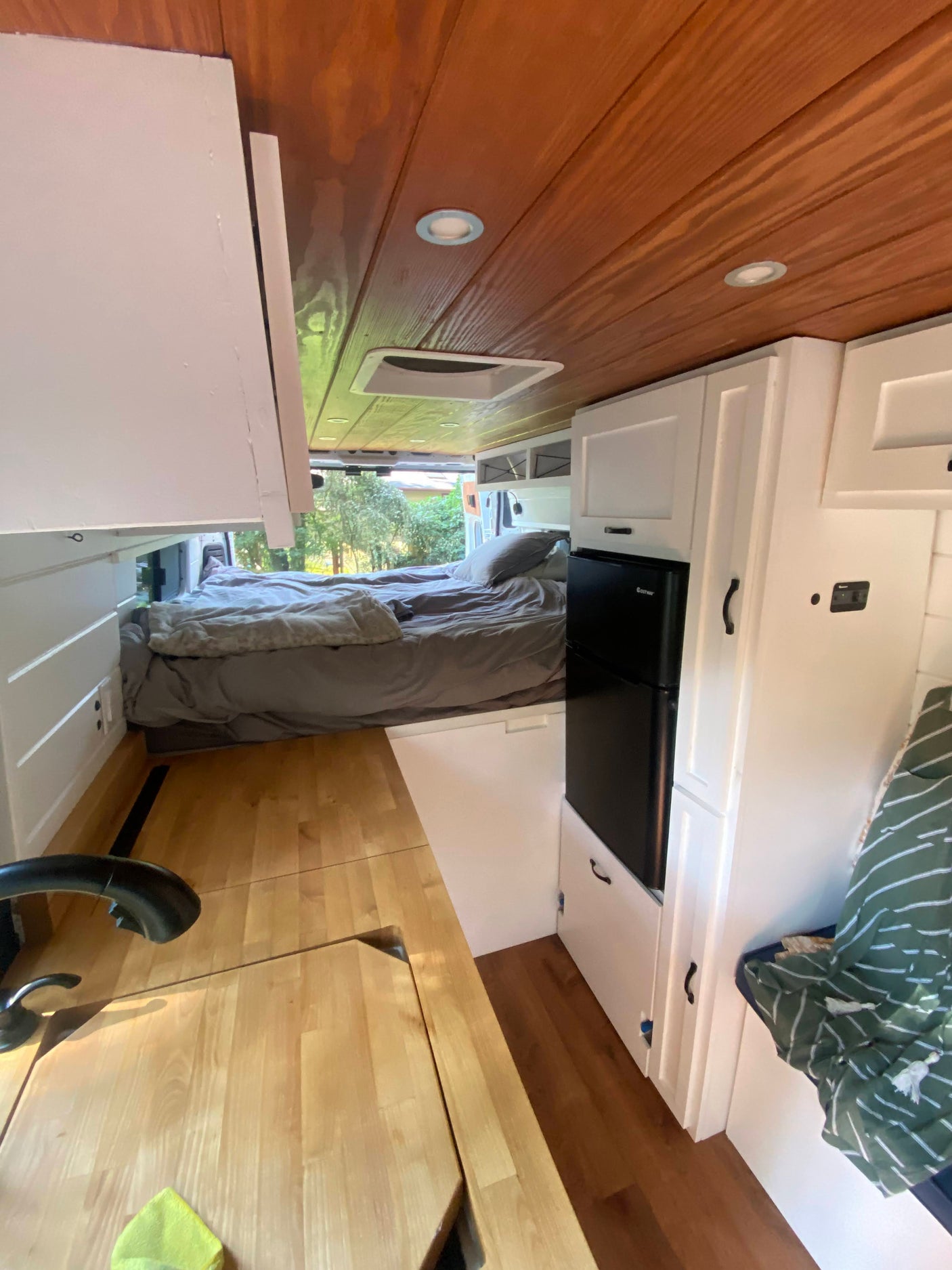 RV rental interior featuring a compact kitchen with fridge, comfy bed, and ample storage within a modern camper van.