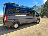 A dark blue camper van on a dirt road, overlooking mountains. Your next rv rental adventure awaits!