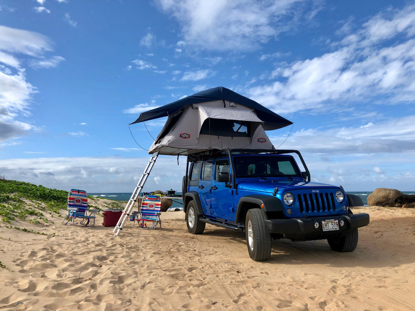 Beach camping setup with a blue Jeep and rooftop tent, perfect for an RV rental adventure by the ocean. — photo 5