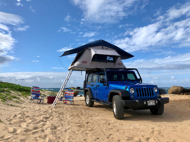 Beach camping setup with a blue Jeep and rooftop tent, perfect for an RV rental adventure by the ocean. — photo 5