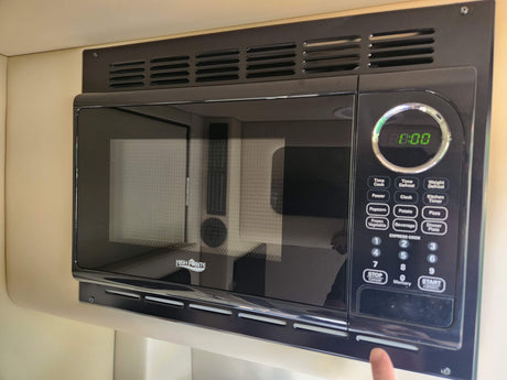 Black High Pointe microwave, built into an RV rental. Features a digital clock and multiple cooking options for travel convenience.