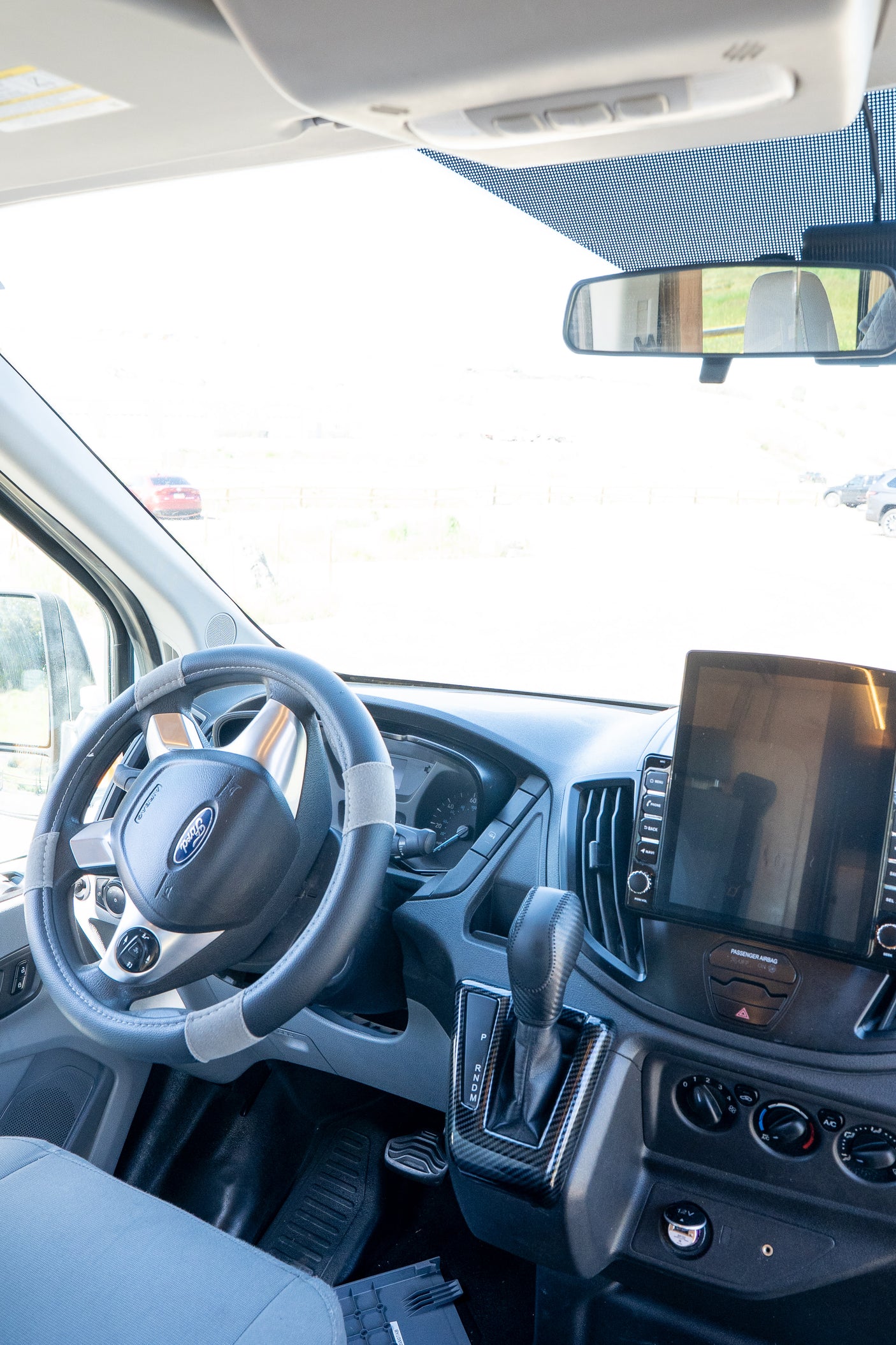 Inside a modern **rv rental** van: driver's cockpit with Ford steering wheel, dashboard, and large display screen.