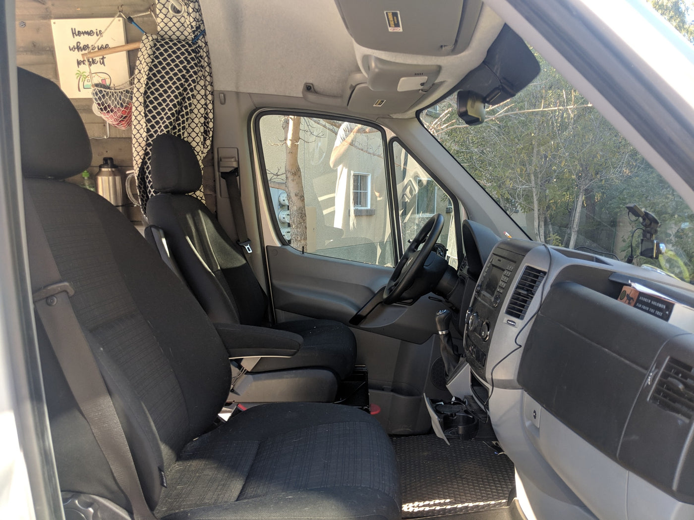 RV rental interior: Front cabin with black seats, steering wheel, dashboard, and a "Home is where we park it" sign. — photo 20