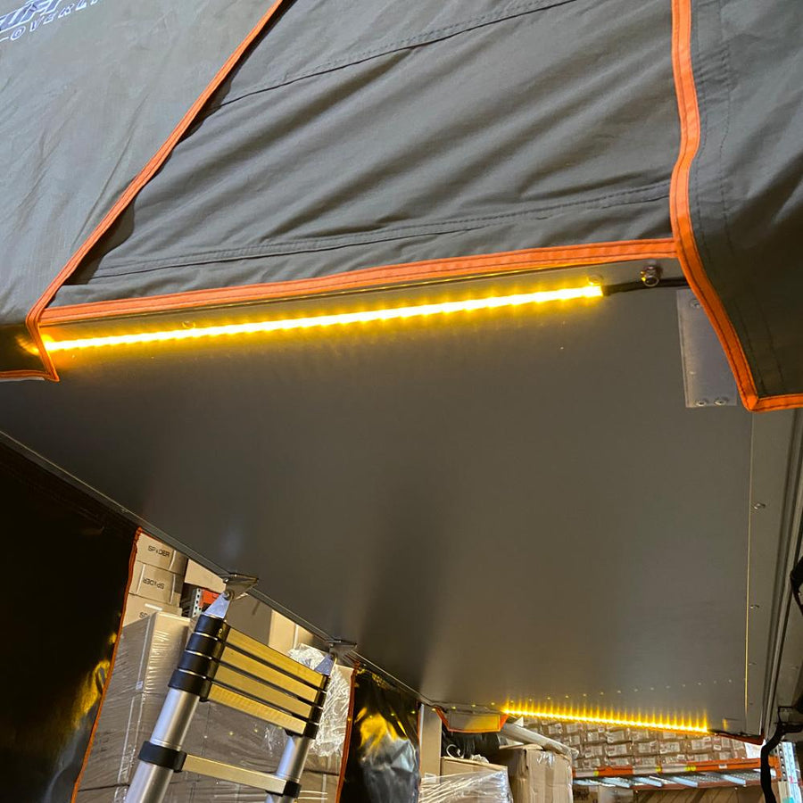  featuring a quilted mattress and walls for a cozy sleep.|User controls bright LED lighting inside a rooftop tent setup