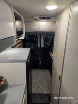 Modern RV rental interior featuring a functional kitchen, convertible sleeping area, and ample storage for travel.
