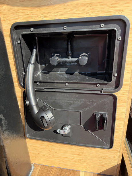 RV rental outdoor shower unit with hot/cold controls, a shower head, hose, and winterizing instructions for easy use.
