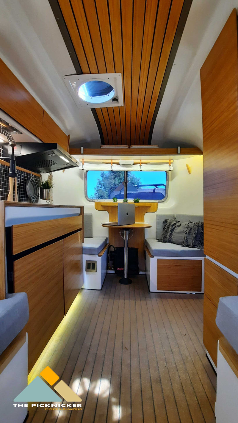 Explore this sleek RV rental interior with a kitchenette, dining nook, and laptop workspace. Ideal for modern glamping journeys. — photo 10