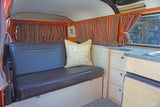 Spacious RV interior featuring a dark bench, striped curtains, and compact kitchen, ideal for your next rv rental trip.