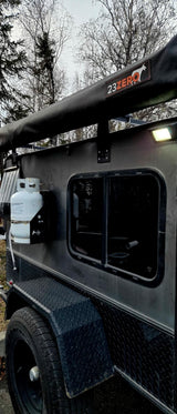 This rugged off-road utility trailer, perfect for RV rental, features a 23ZERO awning, propane tank, and side window.