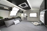 Step inside this cozy RV rental: a modern, compact bedroom with a queen bed, bright windows, AC, and storage.