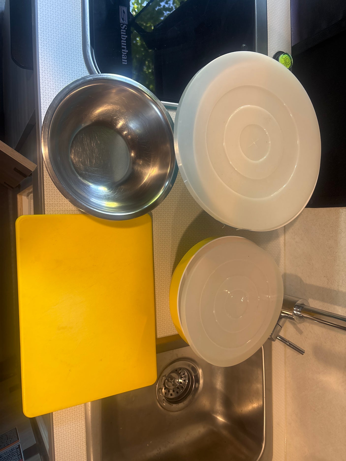 RV rental kitchen supplies: mixing bowl, cutting board, and lidded bowls by the sink. Ready for cooking on the road!