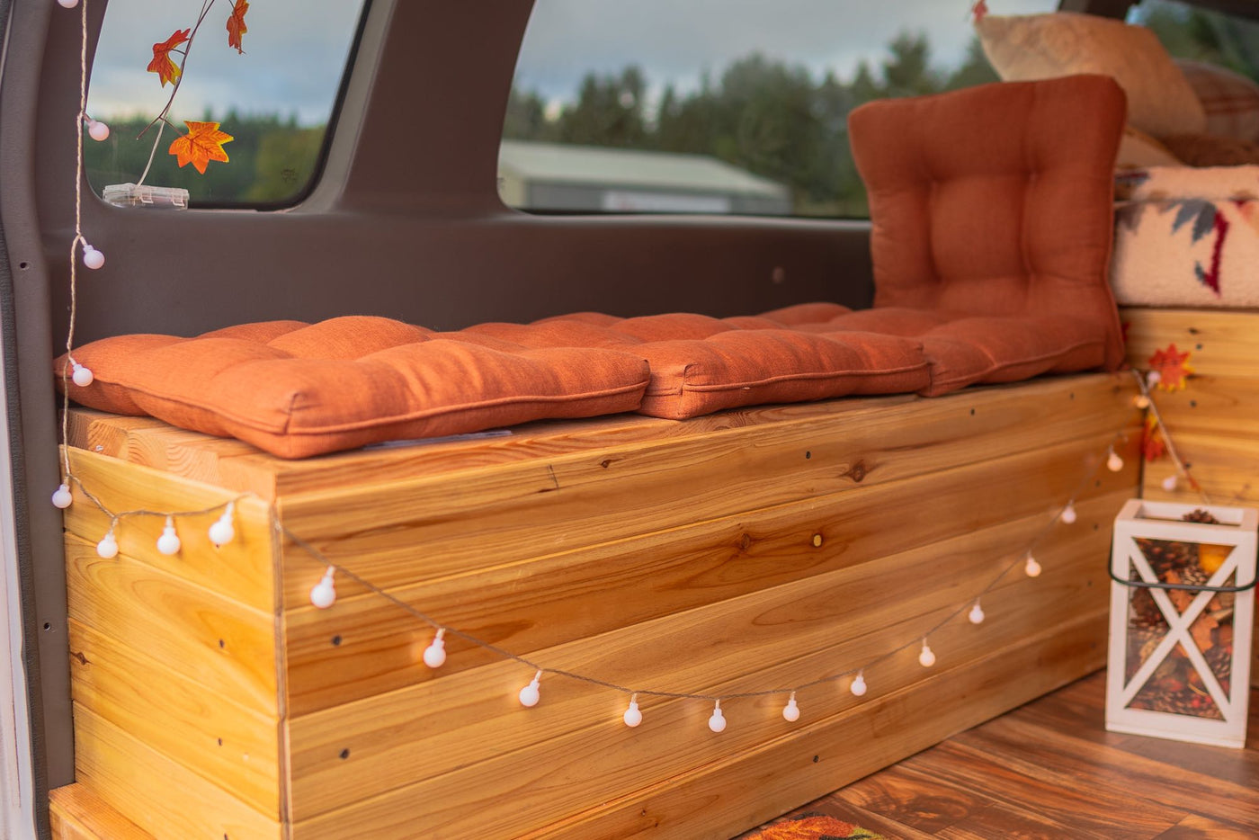  and cooler.|Tan Ford E-Series camper van (RV rental) parked in a lot beside a foggy lake with a tree & picnic area.|Experience outdoor fun! This RV rental camper van's cozy interior — photo 7
