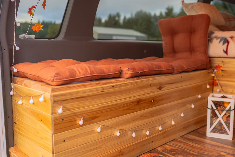  and cooler.|Tan Ford E-Series camper van (RV rental) parked in a lot beside a foggy lake with a tree & picnic area.|Experience outdoor fun! This RV rental camper van's cozy interior — photo 7